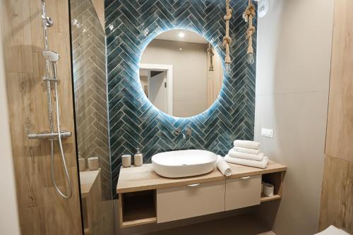 ein Bad mit einem Waschbecken und einem Spiegel in der Unterkunft M&K Apartamenty Morska Fala, Gdańsk - Wyspa Sobieszewska in Danzig