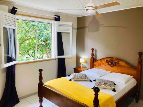 a bedroom with a bed with a yellow blanket and a window at Villa TrÔpik Diamond in Le Diamant