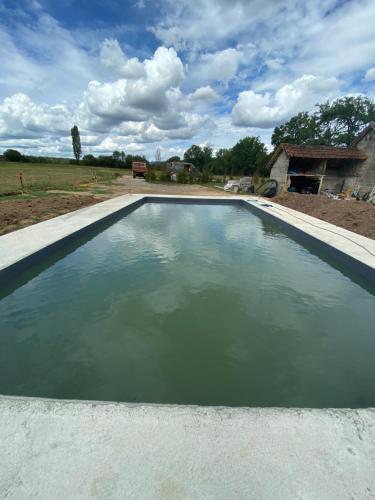 una piscina de agua con una casa en el fondo en Le Moulin de Lassalle, en Curemonte