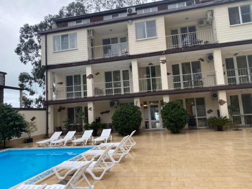 a hotel with chairs and a swimming pool at Guest house Skazka in Gagra