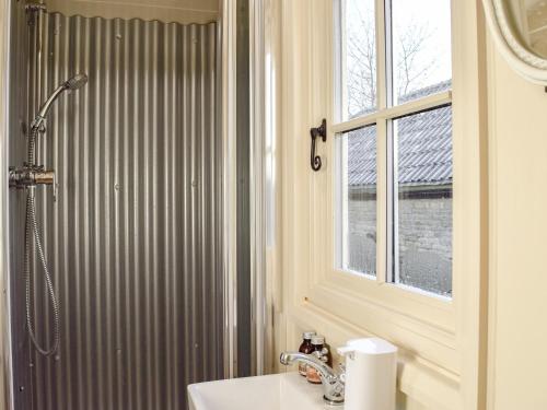 uma casa de banho com um chuveiro, um lavatório e uma janela em Molly The Shepherds Hut em Bampton