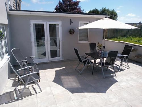 a patio with a table and chairs and an umbrella at Sandy cottage, nr Eden & beaches in St Austell