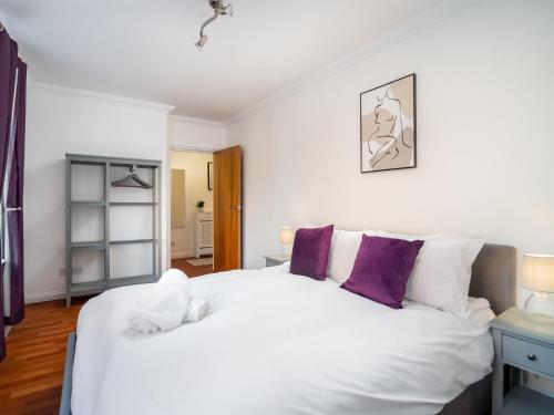 um quarto com uma grande cama branca com almofadas roxas em Pass the Keys Stylish Cosy and Central 1 Bed Flat with Parking em Rickmansworth