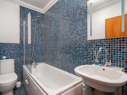 W wyłożonej niebieskimi kafelkami łazience znajduje się umywalka i toaleta. w obiekcie Pass the Keys Stylish Cosy and Central 1 Bed Flat with Parking w mieście Rickmansworth