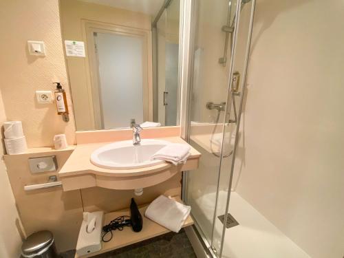 La salle de bains est pourvue d'un lavabo et d'une douche. dans l'établissement Hotel Le Sevigne - Sure Hotel Collection by Best Western, à Rennes
