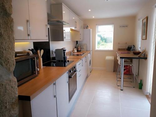 a kitchen with white cabinets and a counter top at Sandy cottage, nr Eden & beaches in St Austell