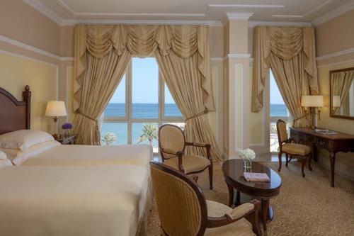 um quarto de hotel com uma cama e uma grande janela em The Regency Hotel Kuwait em Kuwait