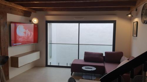 ein Wohnzimmer mit einem Sofa und einem großen Fenster in der Unterkunft SUPERBE T3 AU COEUR DU CENTRE VILLE in Narbonne