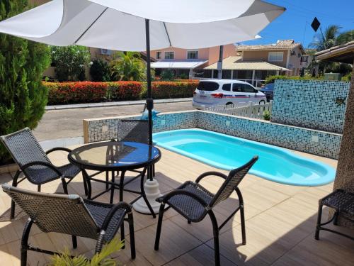 a patio with a table and chairs and an umbrella at Casa 4 quartos, com piscina no Condominio Sol Marina Jacuipe com acesso a praia e ao rio de Jacuipe in Camaçari