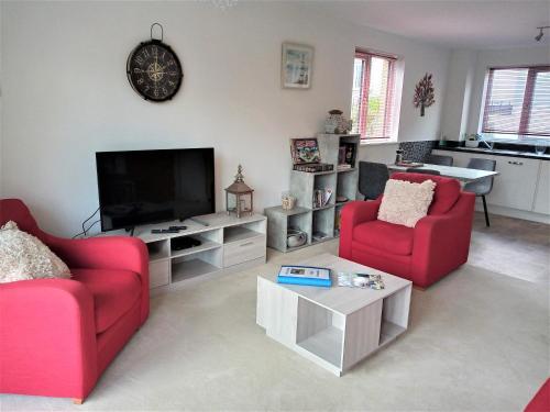 a living room with two red chairs and a flat screen tv at Stunning Apartment, balconies, private beach, coast path in Charlestown