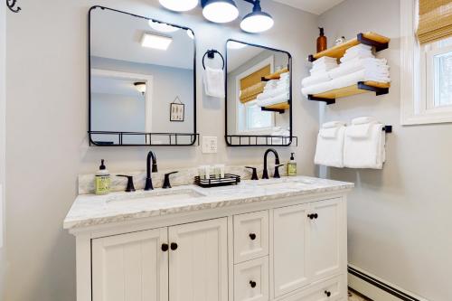 a white bathroom with a sink and two mirrors at Deer Run Retreat in Gilford
