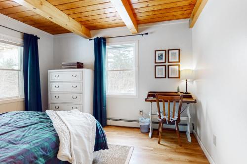 a bedroom with a bed and a desk and windows at Deer Run Retreat in Gilford
