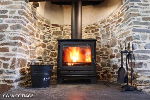a fireplace in a stone wall with a stove at Cobb Cottage - HiddenDevon in Winkleigh
