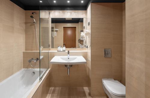 a bathroom with a sink and a tub and a toilet at Hotel Castle Garden in Budapest