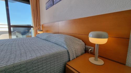 1 dormitorio con 1 cama y 1 lámpara en una mesa en En el centro de Benidorm y con vistas al mar, en Benidorm