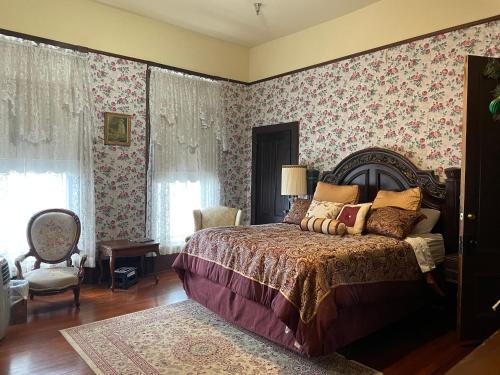 a bedroom with a bed and floral wallpaper at Grand Gables Inn in Palatka