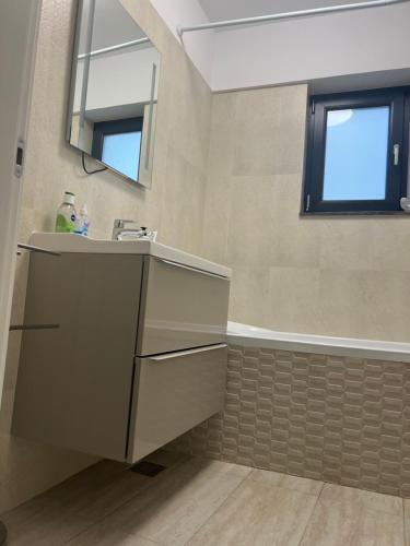 een badkamer met een wastafel en een bad bij Apartament Otopeni lângă parc in Otopeni