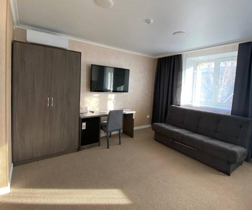 a hotel room with a couch and a desk and a television at Skif HOTEL & SPA in Petropavlovsk