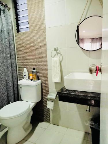 a bathroom with a toilet and a sink and a mirror at Natalie's Villa in Iloilo City