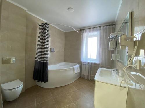 a bathroom with a tub and a toilet and a sink at Skif HOTEL & SPA in Petropavlovsk