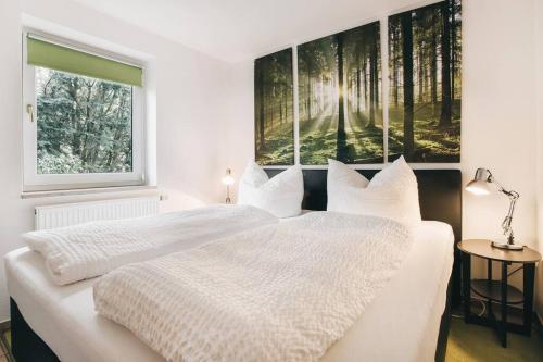 a white bedroom with two beds and a window at Ferienhaus an der Wiederitz in Freital
