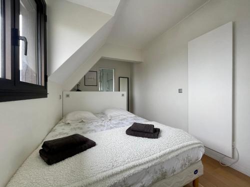 1 dormitorio con 1 cama blanca y 2 toallas negras. en Deauville Harmonie - Tout à pied, Balcon & Modernité, en Deauville