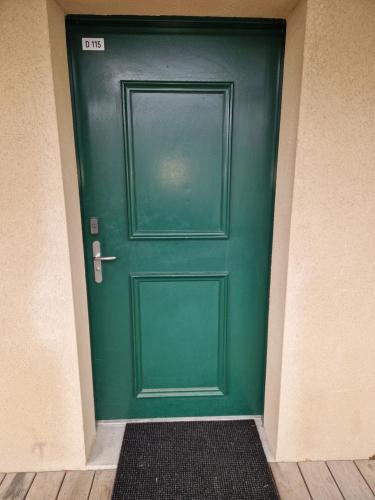 uma porta verde num corredor com um tapete à frente em Joli T2 avec piscine aux portes de Honfleur em Équemauville