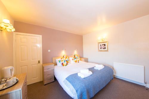 sypialnia z dużym łóżkiem i niebieskim kocem w obiekcie Dalesgate Hotel - Self Check In w mieście Keighley