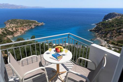 een balkon met een tafel en stoelen en de oceaan bij Kounenos Apartments in Istron