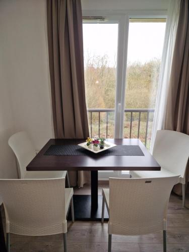d'une table, de chaises, d'une fenêtre et d'un balcon. dans l'établissement Joli T2 avec piscine aux portes de Honfleur, à Équemauville