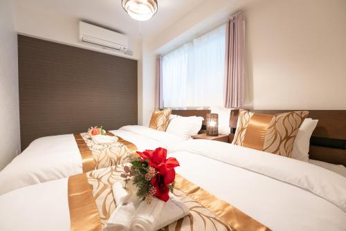 Cette chambre d'hôtel comprend 3 lits avec des fleurs. dans l'établissement GN98 Saiwaicho Osak, à Osaka