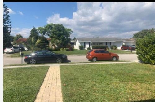 two cars parked in a parking lot in front of a house at room & private bathroom in Boca Raton