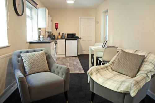 a living room with two chairs and a kitchen at Guest Homes - Clacton Coastal Hideaway in Clacton-on-Sea