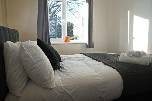 - une chambre avec un lit blanc avec des oreillers et une fenêtre dans l'établissement Guest Homes - Clacton Coastal Hideaway, à Clacton-on-Sea