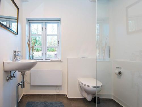 a white bathroom with a toilet and a sink at Holiday home Allingåbro XXIV in Allingåbro