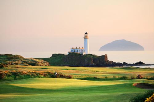 a view of a golf course with a lighthouse at Trump Turnberry in Turnberry