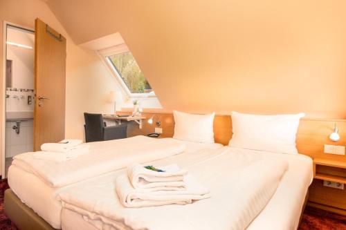 a hotel room with two beds with white towels on them at Waldhotel Schinkenwirt in Olsberg