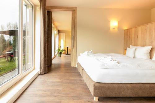 a bedroom with a large bed and a large window at Waldhotel Schinkenwirt in Olsberg