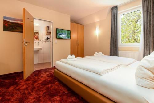 a hotel room with two beds and a bathroom at Waldhotel Schinkenwirt in Olsberg