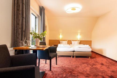 a hotel room with two beds and a table at Waldhotel Schinkenwirt in Olsberg