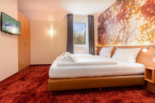 a bedroom with a large white bed with a window at Waldhotel Schinkenwirt in Olsberg