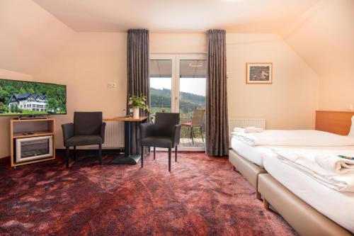 a hotel room with a bed and a table and chairs at Waldhotel Schinkenwirt in Olsberg