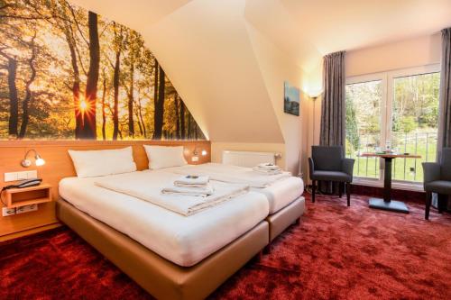 a hotel room with a bed and a large window at Waldhotel Schinkenwirt in Olsberg
