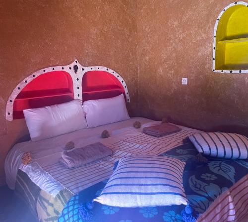 - une chambre avec un lit à tête rouge dans l'établissement Dar Yaya, à M'Hamid El Ghizlane