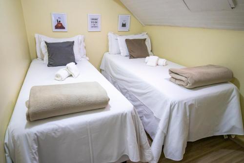 two beds in a room with white sheets and towels at Green Village Hotel in Monte Verde