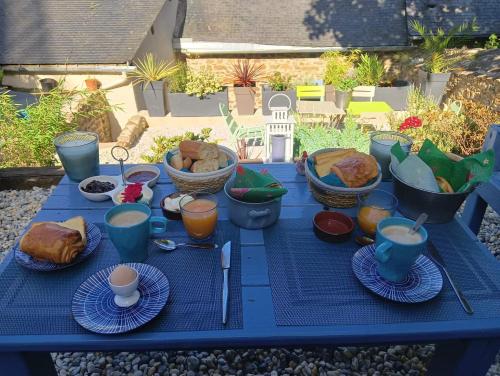 Chambre d'hote Familiale de la maison Bleue في Lanvallay: طاولة زرقاء عليها طعام ومشروبات