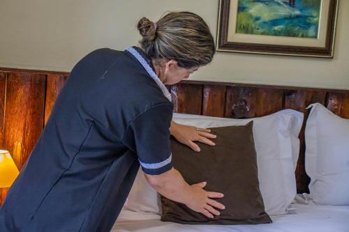a woman putting a pillow on a bed at Green Village Hotel in Monte Verde
