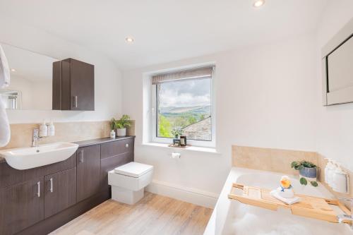 La salle de bains est pourvue d'un lavabo, de toilettes et d'une fenêtre. dans l'établissement Weavers Cottage, Sleeps 4, town centre, à Kirkby Lonsdale