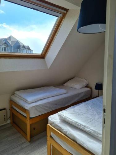 deux lits jumeaux dans une chambre avec fenêtre dans l'établissement Appartement au bord de mer, à Carnac