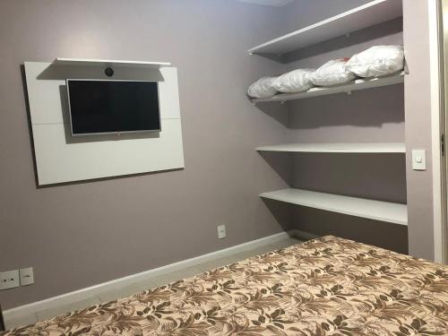 ein Schlafzimmer mit einem Bett und einem TV an der Wand in der Unterkunft Residencial a Beira Mar Pero in Cabo Frio